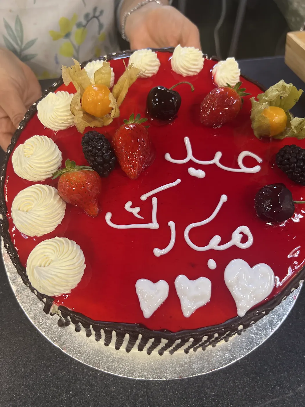 Red glazed cake with fresh fruit and cream rosettes