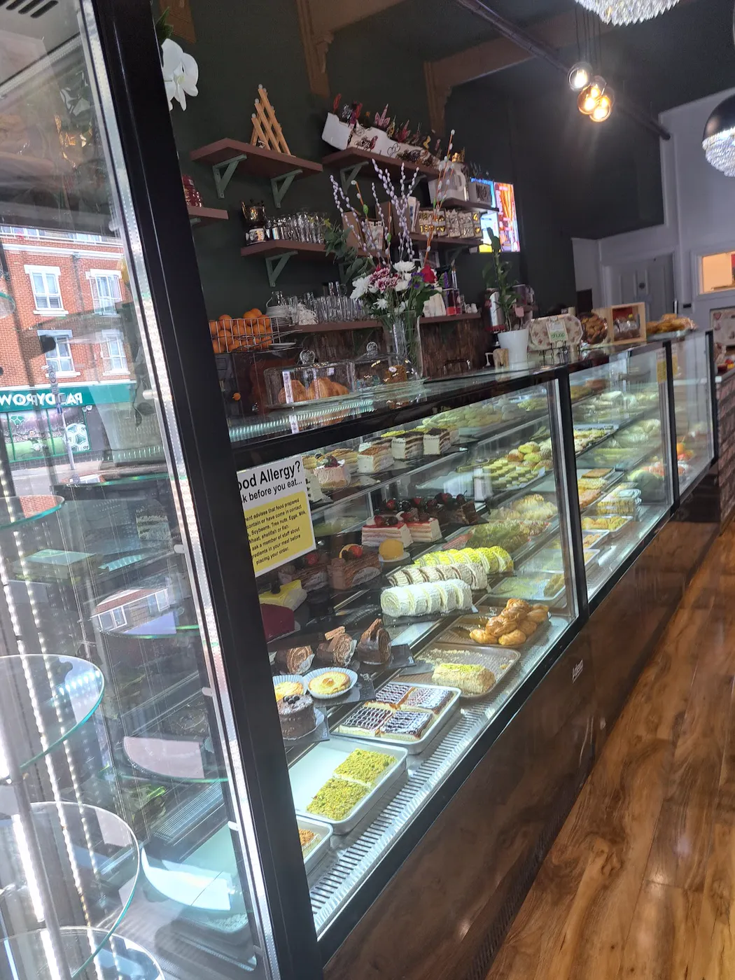 Inside the shop: a long glass counter of cakes and pastries